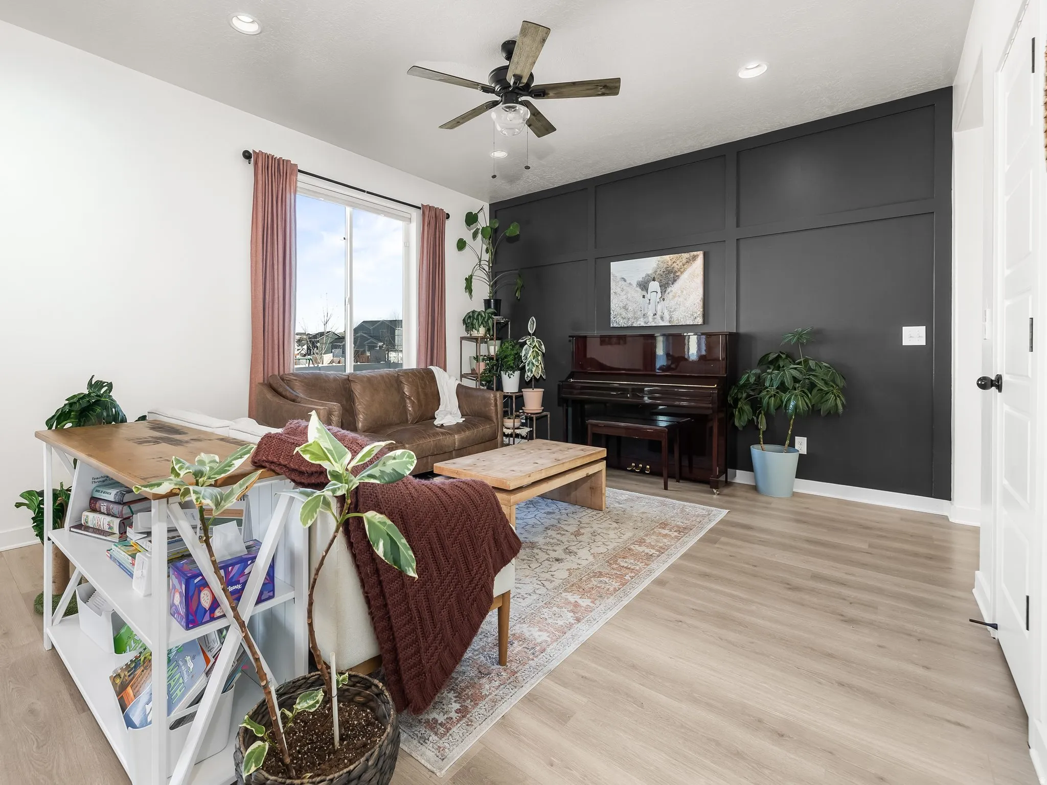 Living area with a ceiling fan, light wood-type flooring, a decorative wall, and recessed lighting
