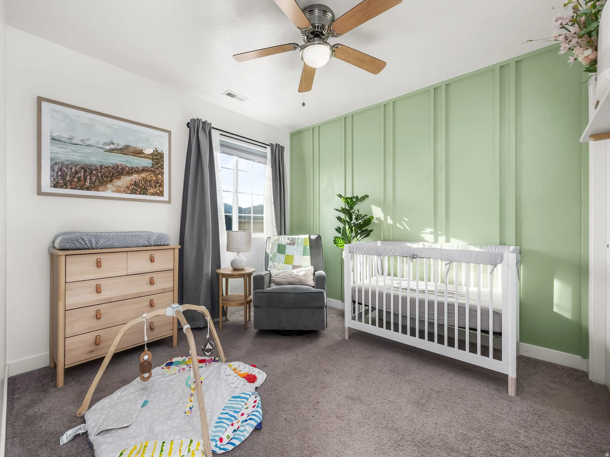 Bedroom featuring a crib, dark carpet, and ceiling fan