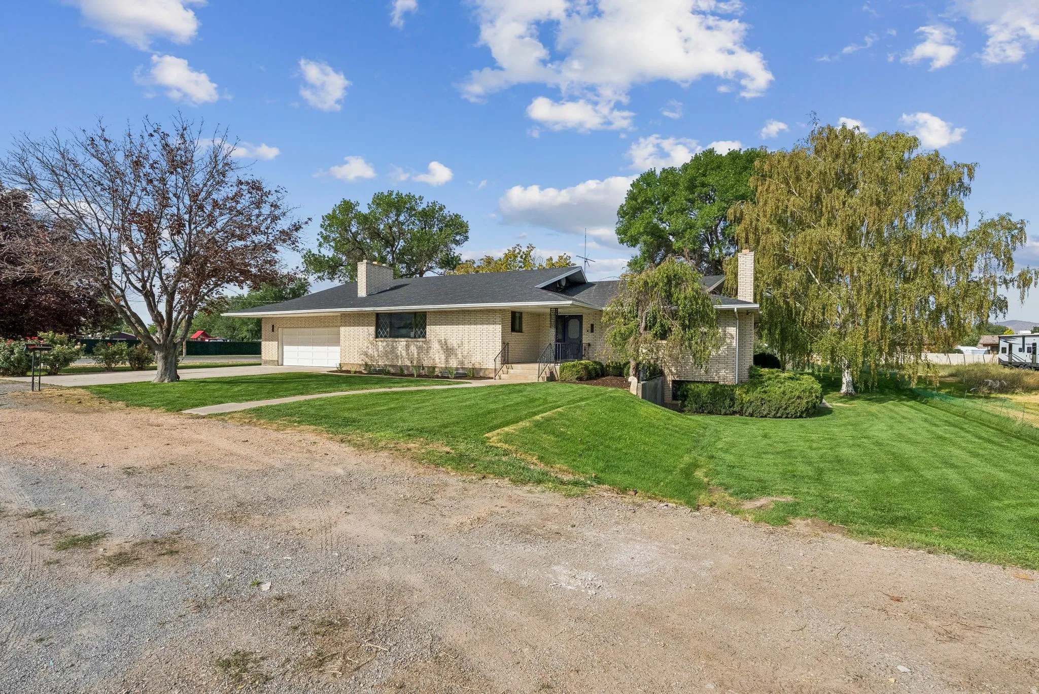 View of front of property featuring dirt driveway, a front lawn, a chimney, and an attached garage