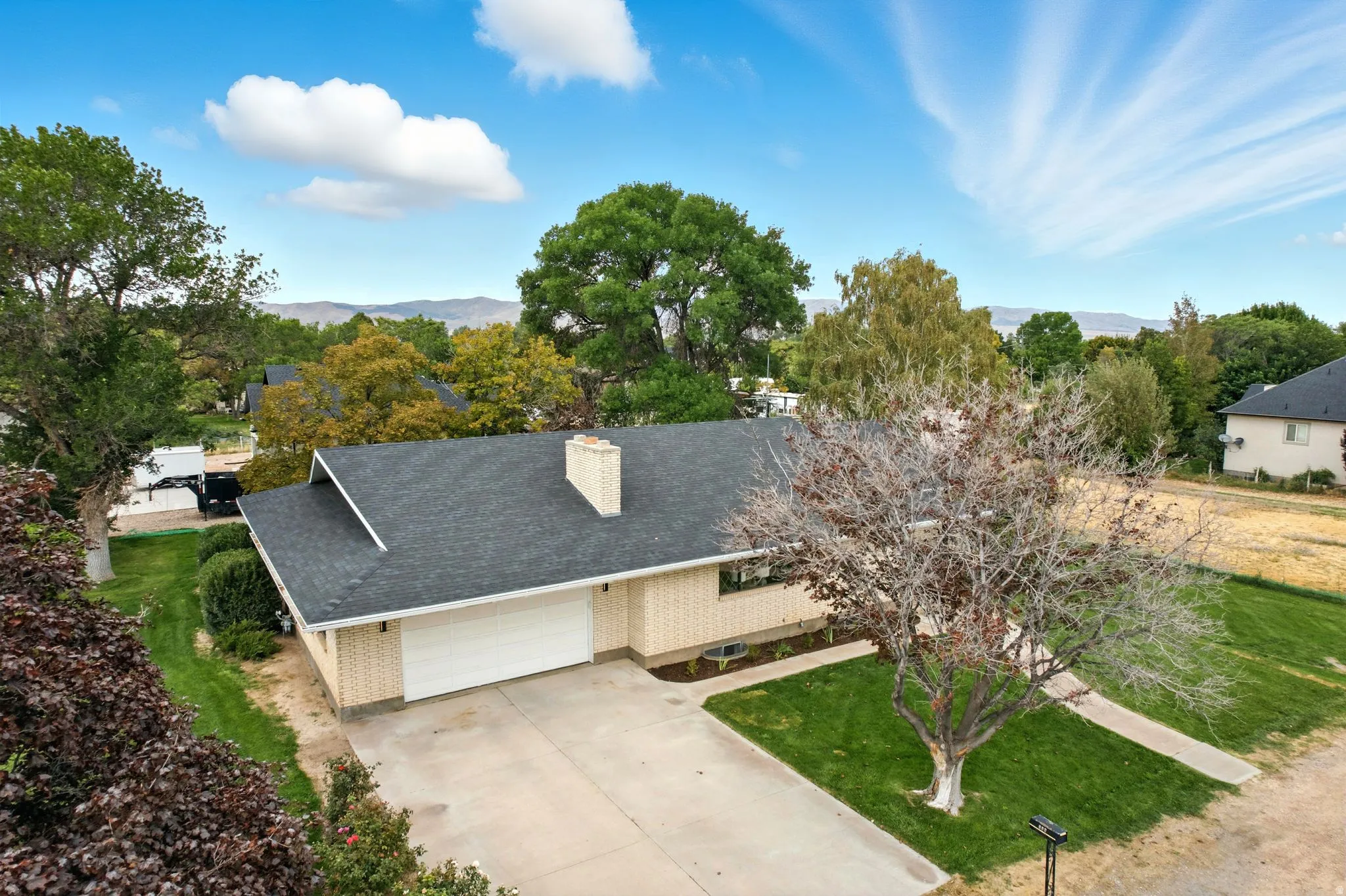 View of front of home with a garage, concrete driveway, a front lawn, a shingled roof, and a chimney