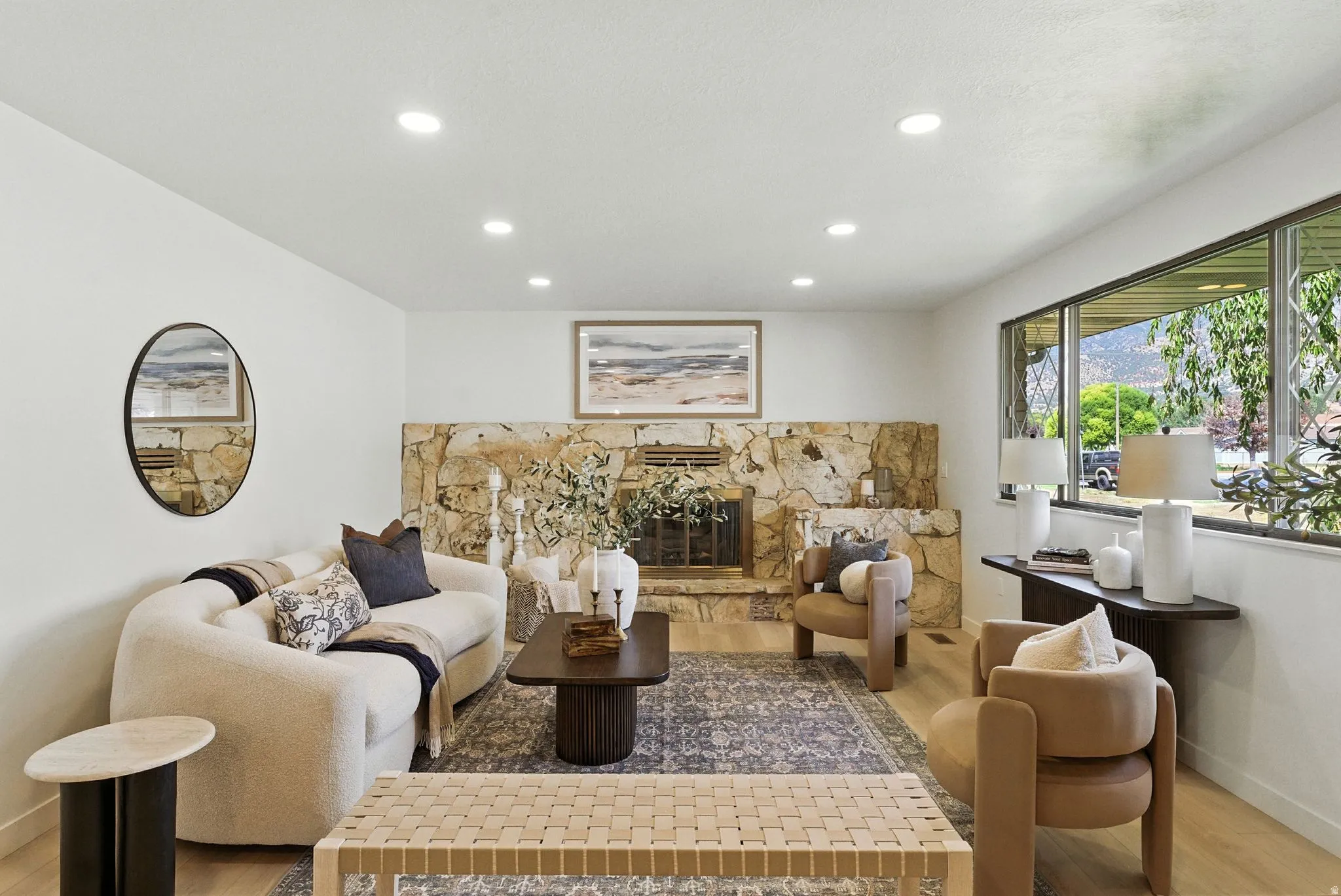Living room featuring light wood-type flooring, a stone fireplace, and recessed lighting
