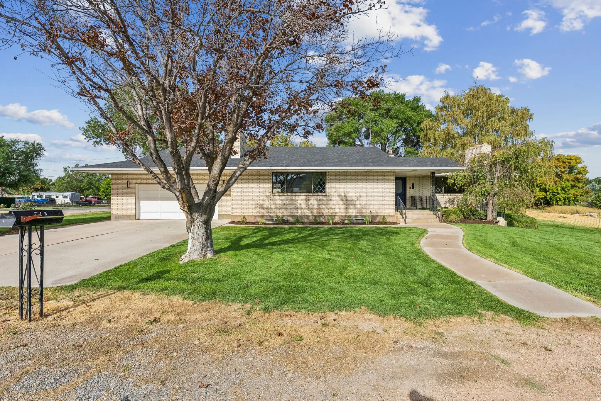 View of front of house featuring a front lawn, brick siding, concrete driveway, an attached garage, and a porch