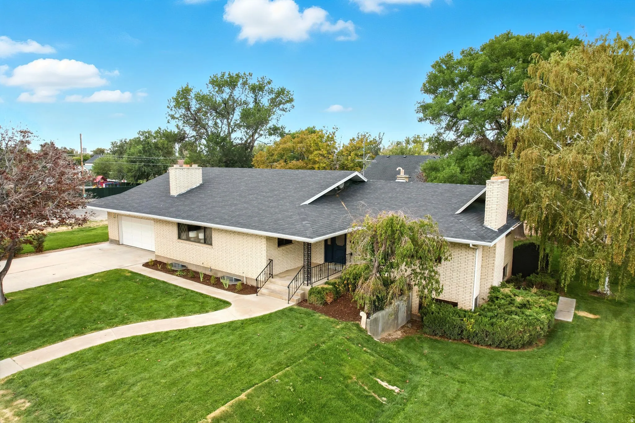 Single story home with a chimney, a front lawn, brick siding, and a garage