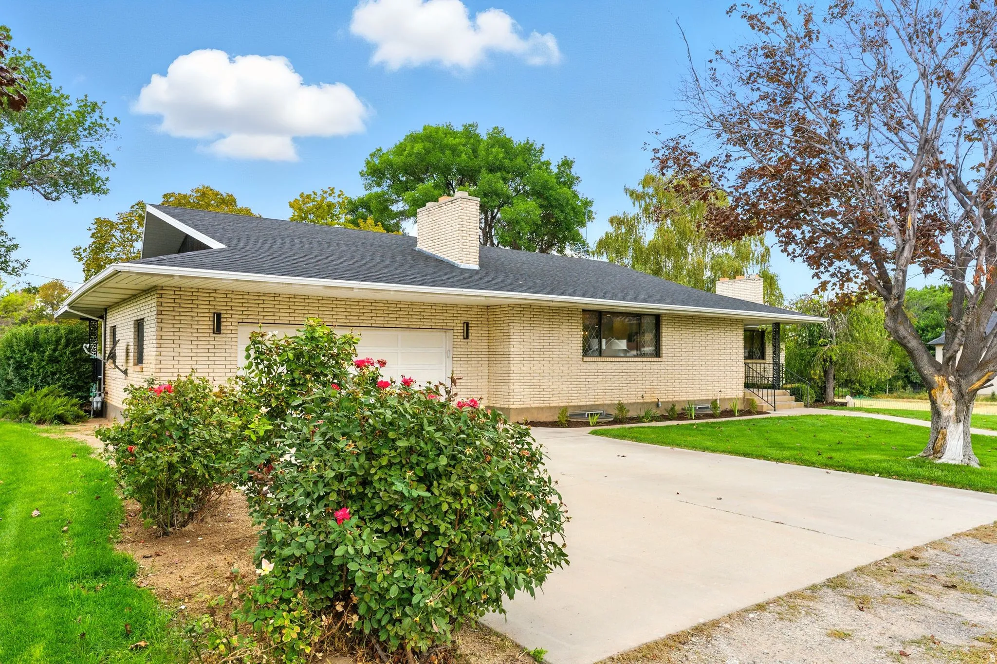 Single story home with a front yard, a chimney, an attached garage, brick siding, and concrete driveway