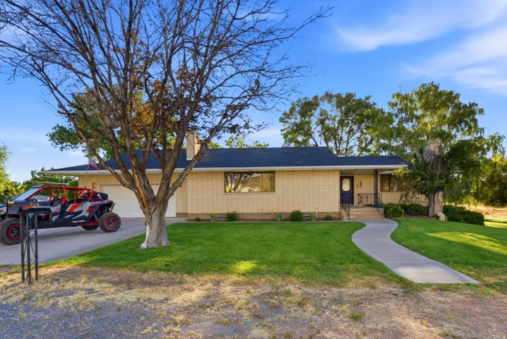 Brick ranch-style exterior featuring a dark blue entry door, an attached two-car garage, a curving concrete pathway, and a manicured front lawn