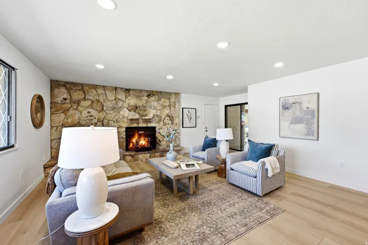 Living area featuring a stone accent wall, recessed lighting, and light wood-finish flooring