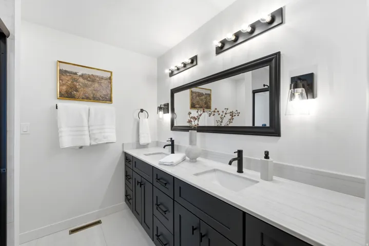 Dual vanity with black cabinetry, integrated sinks, and light-toned countertops