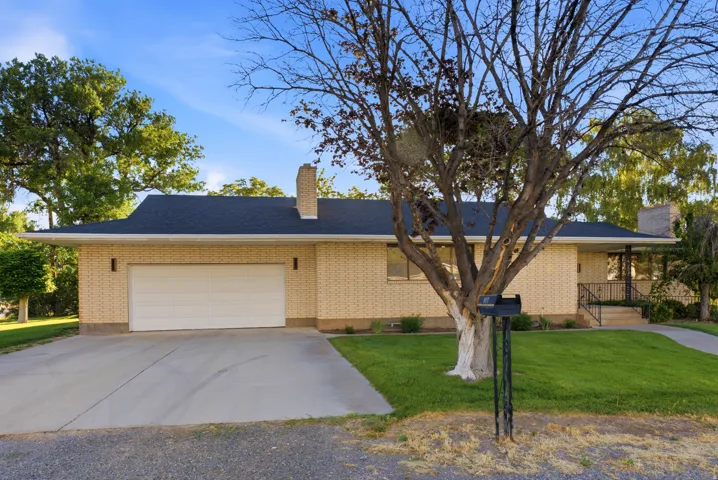 Brick exterior residence featuring a black shingle roof, integrated garage with a white door, and a concrete driveway