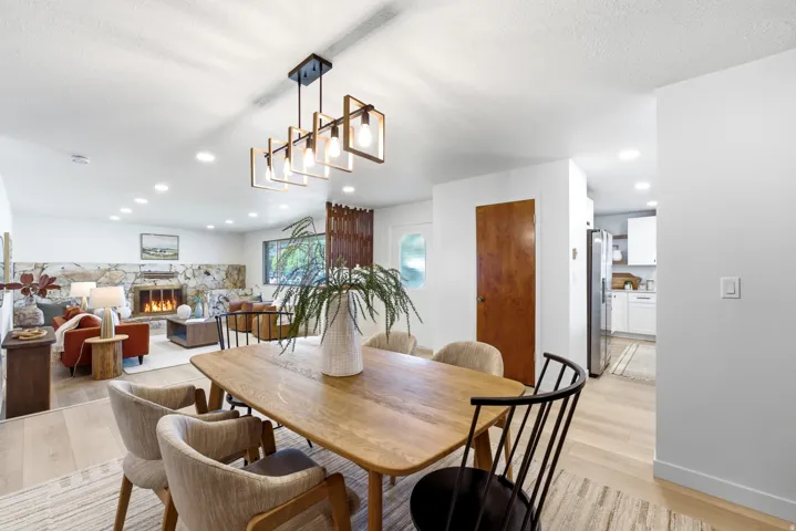 Open-concept living space featuring light wood-finish flooring, recessed lighting, and a linear chandelier