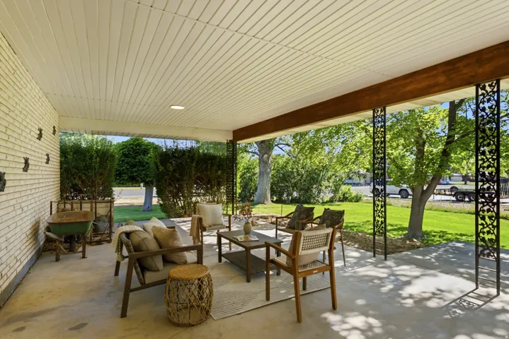 Covered patio featuring a concrete slab, white brick exterior, and decorative wrought iron columns