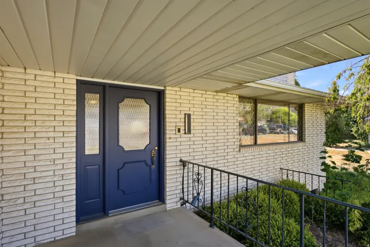 Covered entryway featuring a navy blue front door with decorative glass inserts and a matching sidelight