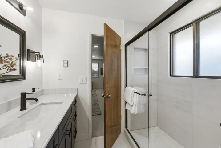 White tile shower with glass enclosure and built-in shelving