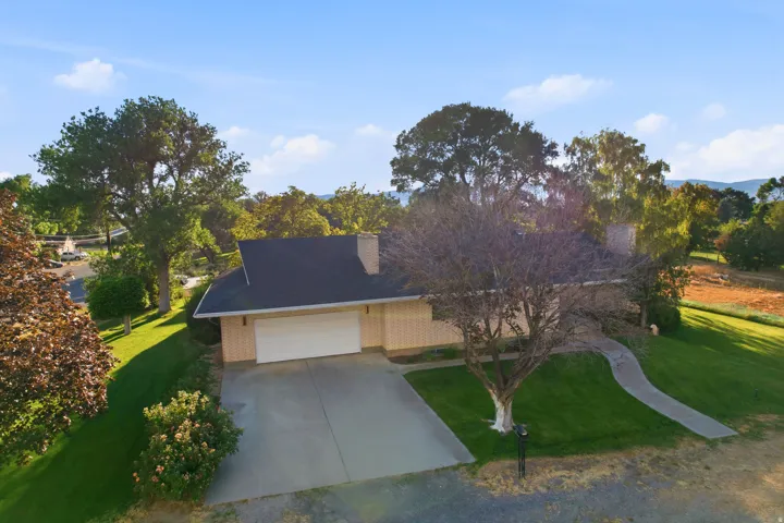 Single-story residence featuring an attached garage, paved driveway, and established landscaping