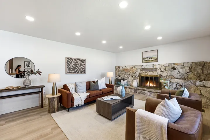 Living area featuring a floor-to-ceiling stone fireplace, recessed lighting, and wood-finish flooring