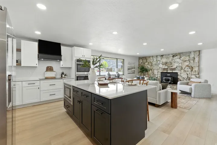 Kitchen with two tone cabinets, a kitchen island, light wood-style floors, stainless steel appliances, and open floor plan