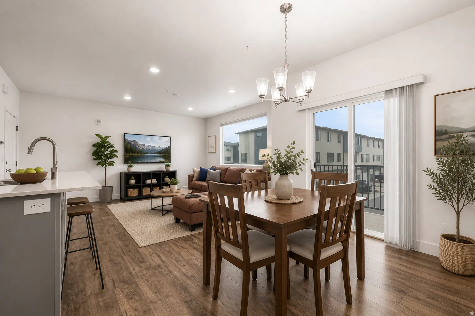 Open-concept living space with wood-finish flooring, recessed lighting, and a sliding glass door to an outdoor balcony