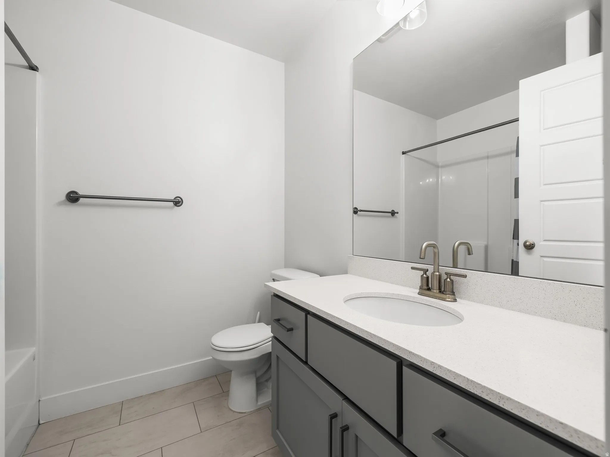 Full bath featuring vanity, light tile patterned floors, and washtub / shower combination
