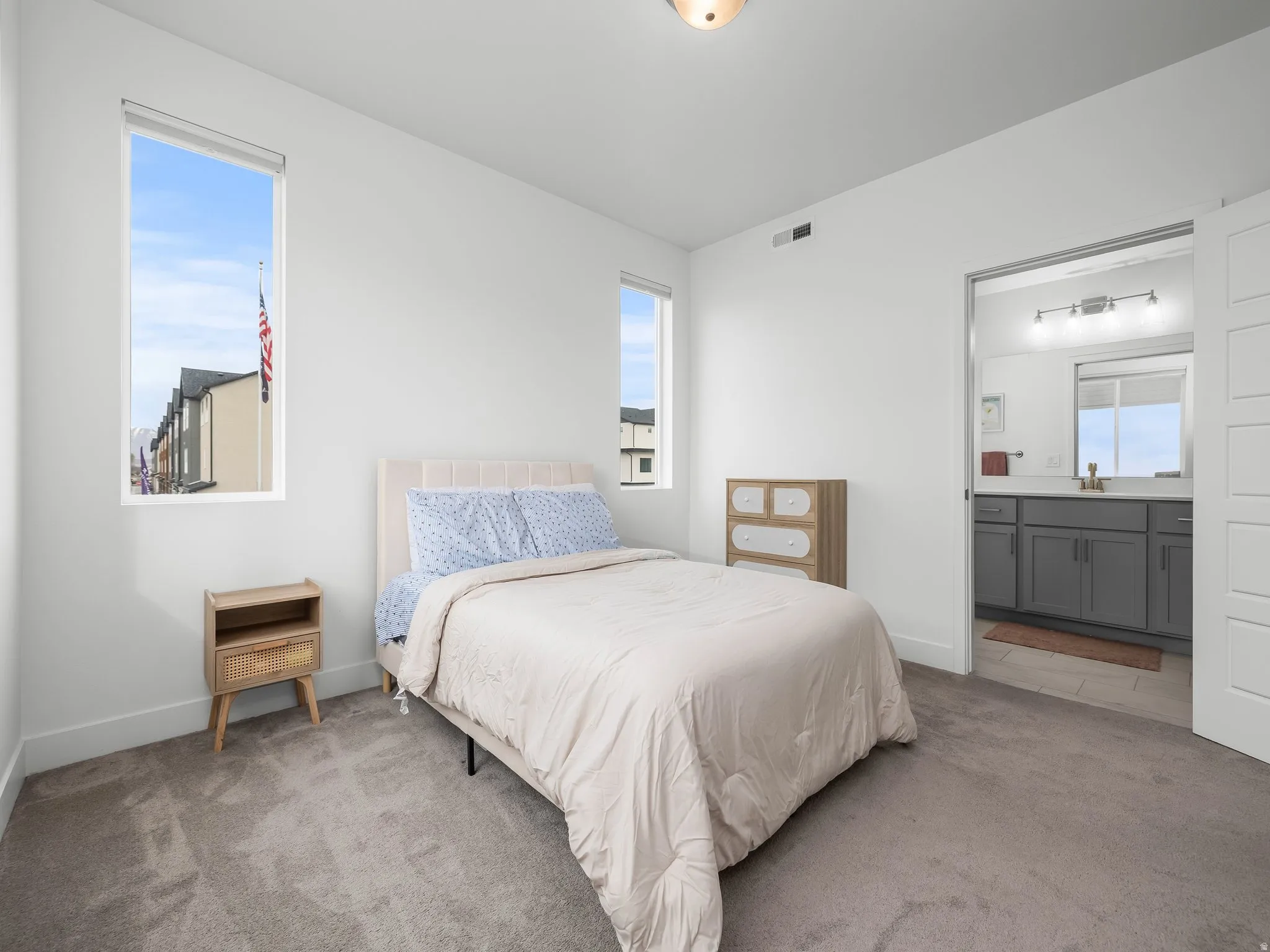 Bedroom featuring carpet floors, multiple windows, and ensuite bathroom