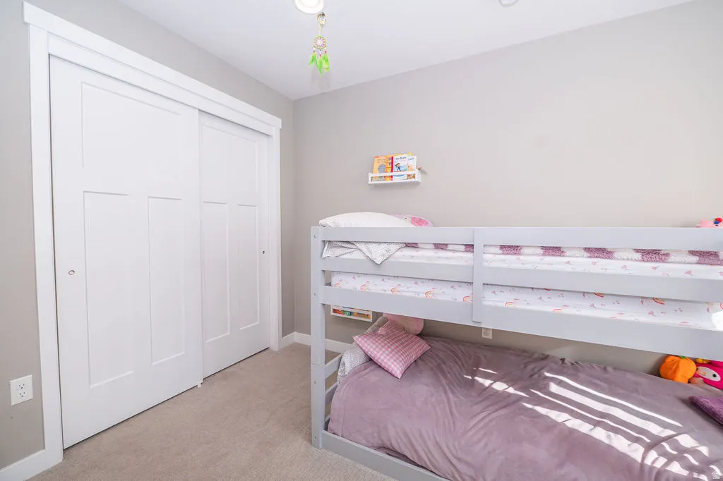 Bedroom with light carpet and a closet