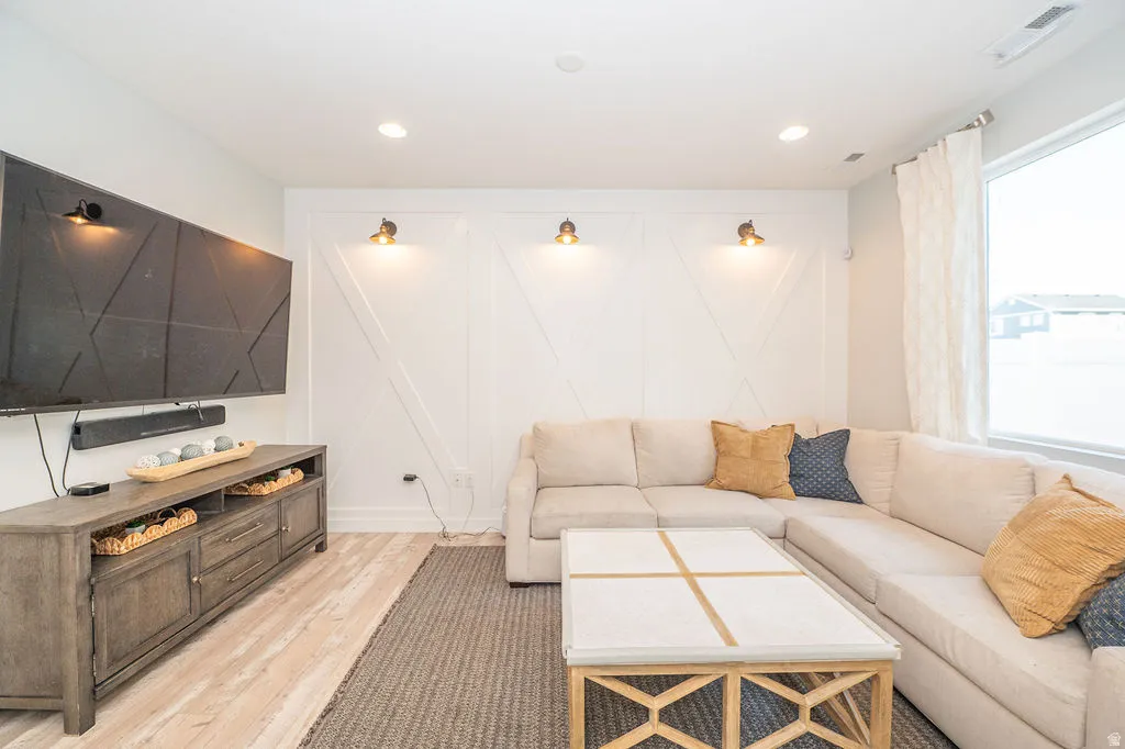Living area with light wood-style flooring, a decorative wall, and recessed lighting