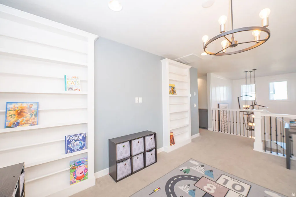 Playroom with suspended lighting, light carpet, and built in shelves