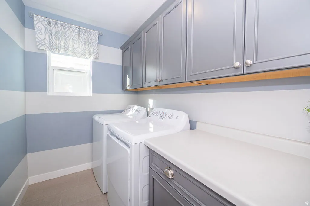 Laundry room with washing machine and clothes dryer, cabinet space, and light tile patterned flooring