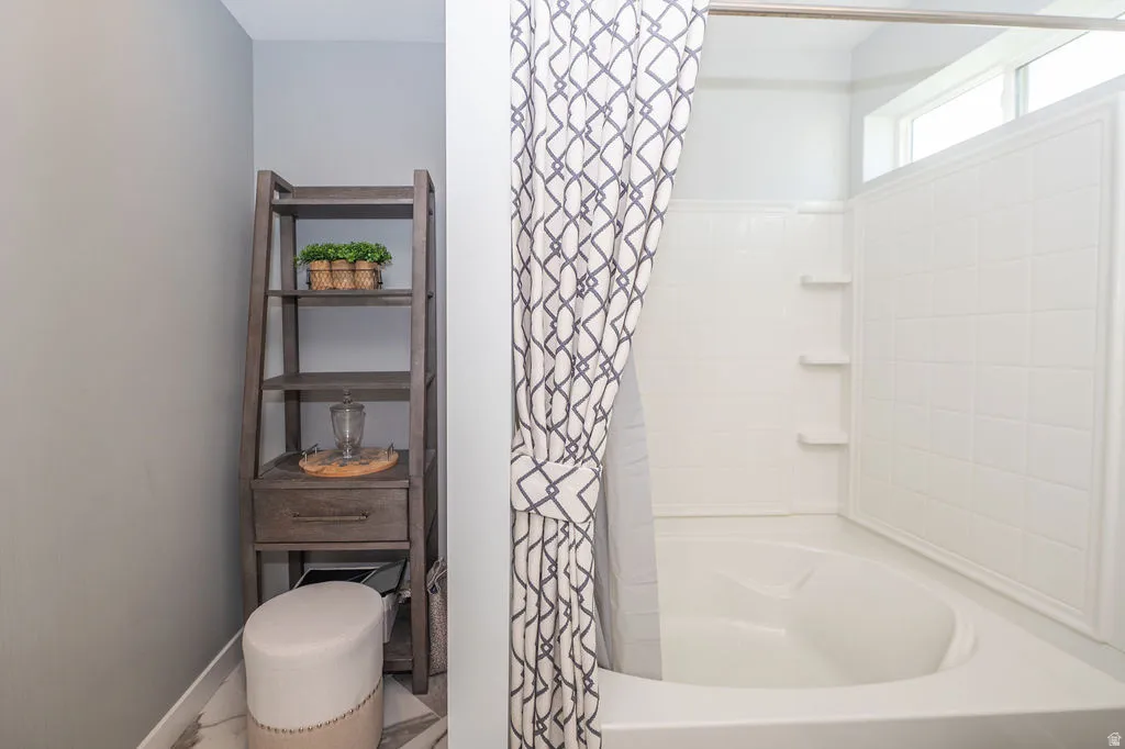 Full bath with baseboards and shower / bathtub combination with curtain