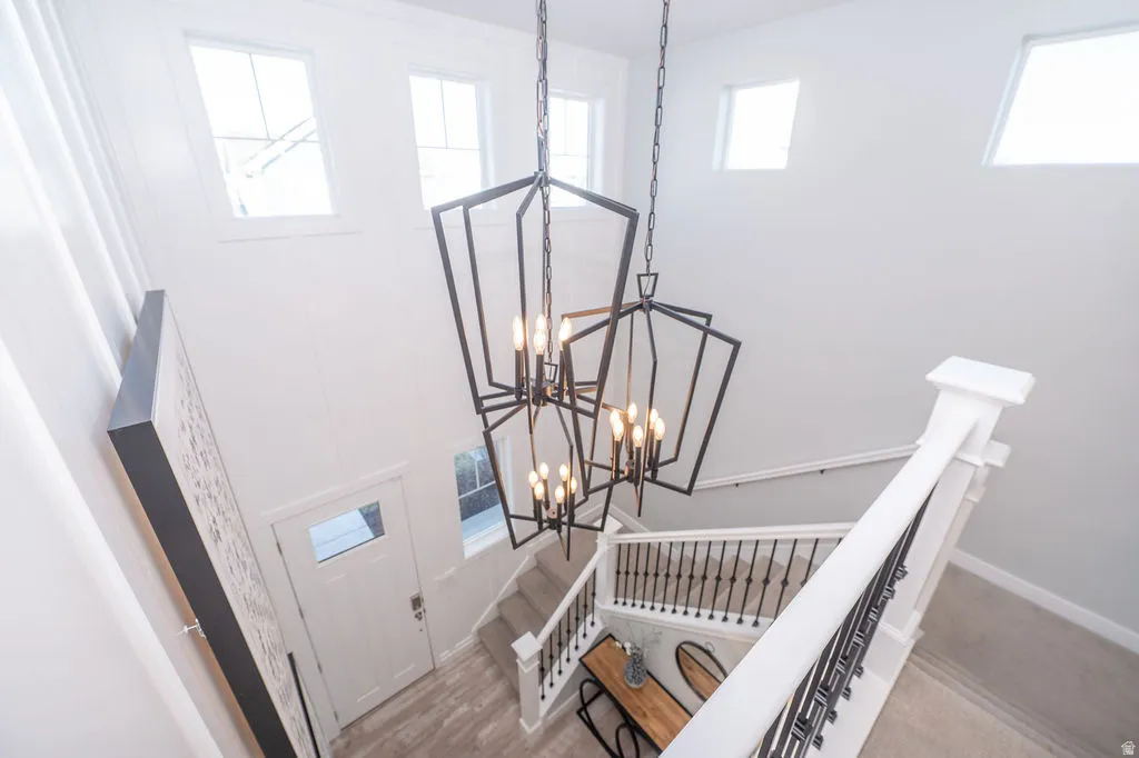 Staircase featuring suspended lighting, a high ceiling, and wood finished floors