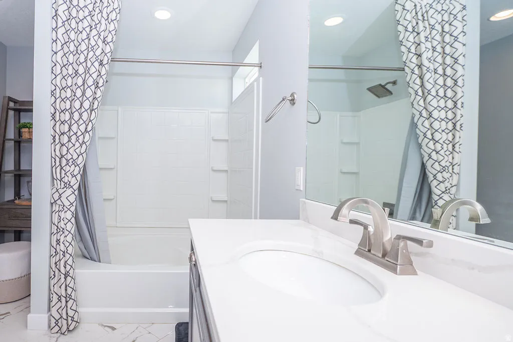 Full bath with shower / bath combo with shower curtain, vanity, and recessed lighting