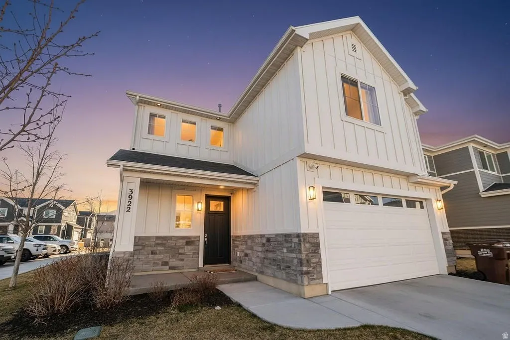 Modern inspired farmhouse featuring board and batten siding, an attached garage, and driveway