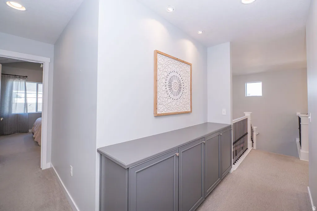 Corridor featuring light colored carpet, an upstairs landing, and recessed lighting