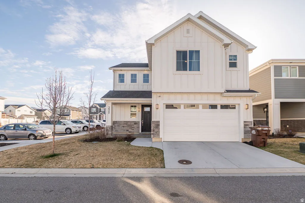 Modern farmhouse style home featuring board and batten siding, stone siding, an attached garage, and driveway