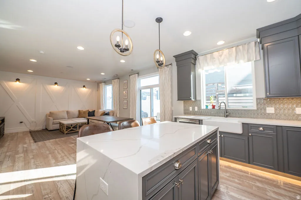 Kitchen with light stone countertops, light wood-type flooring, open floor plan, and a center island