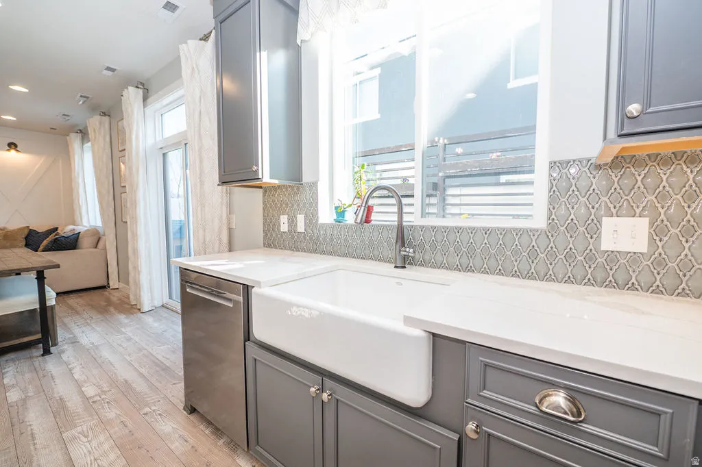 Kitchen featuring gray cabinets, stainless steel dishwasher, light wood-style floors, and recessed lighting