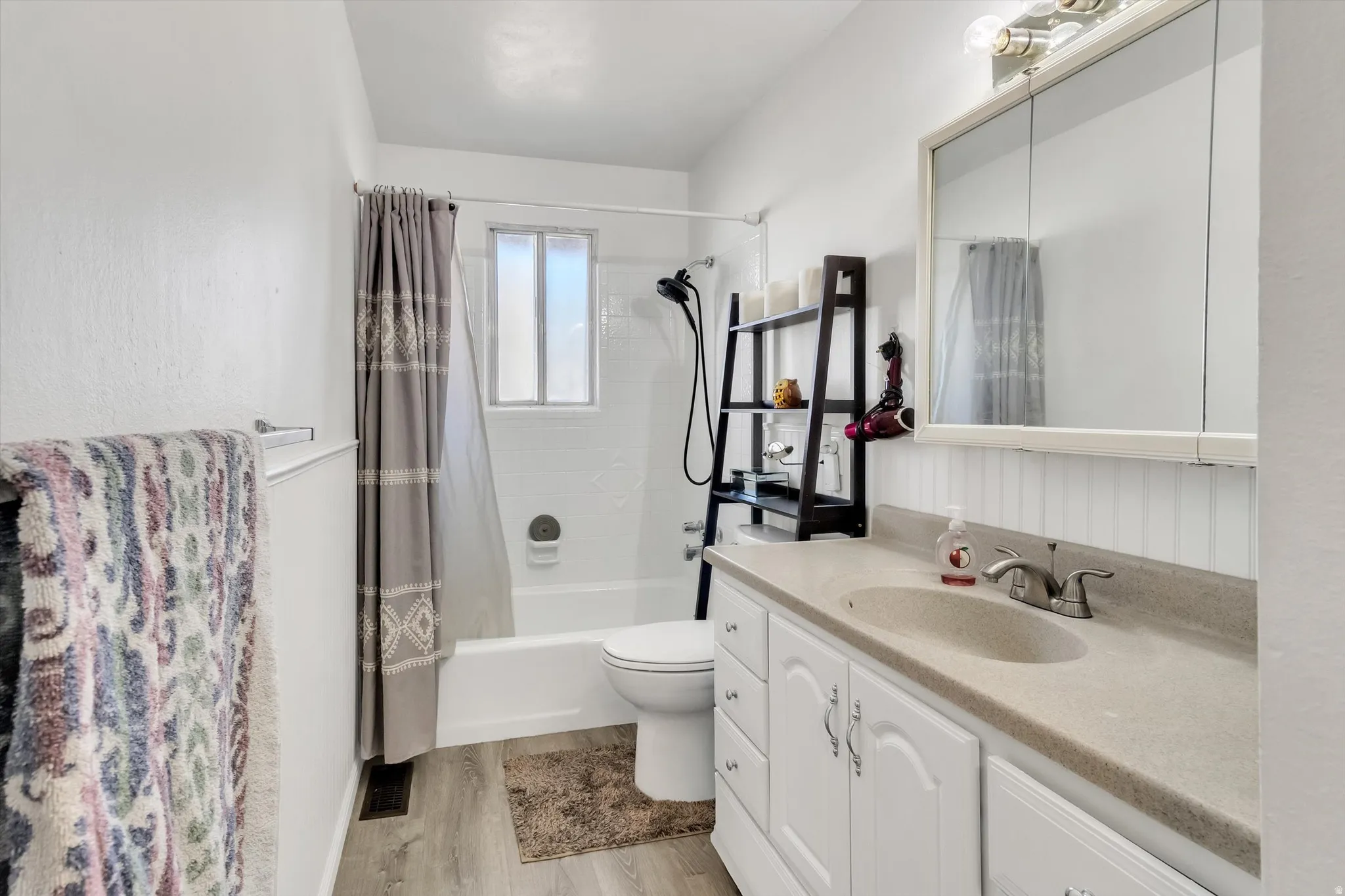 Full bath featuring vanity, light wood-type flooring, and shower / bath combination with curtain