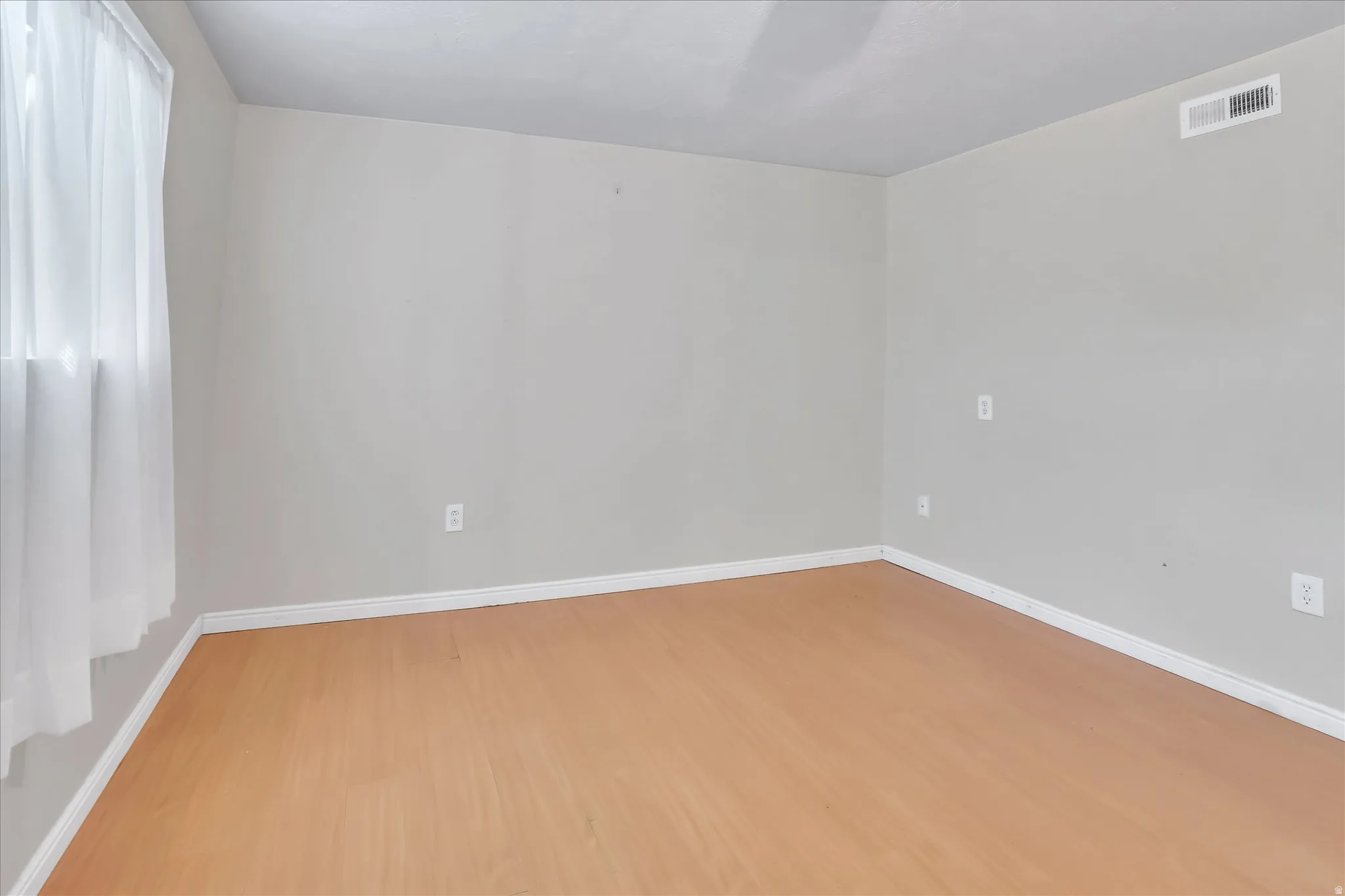 Bright interior space featuring light-toned walls, wood-finish flooring, and white trim
