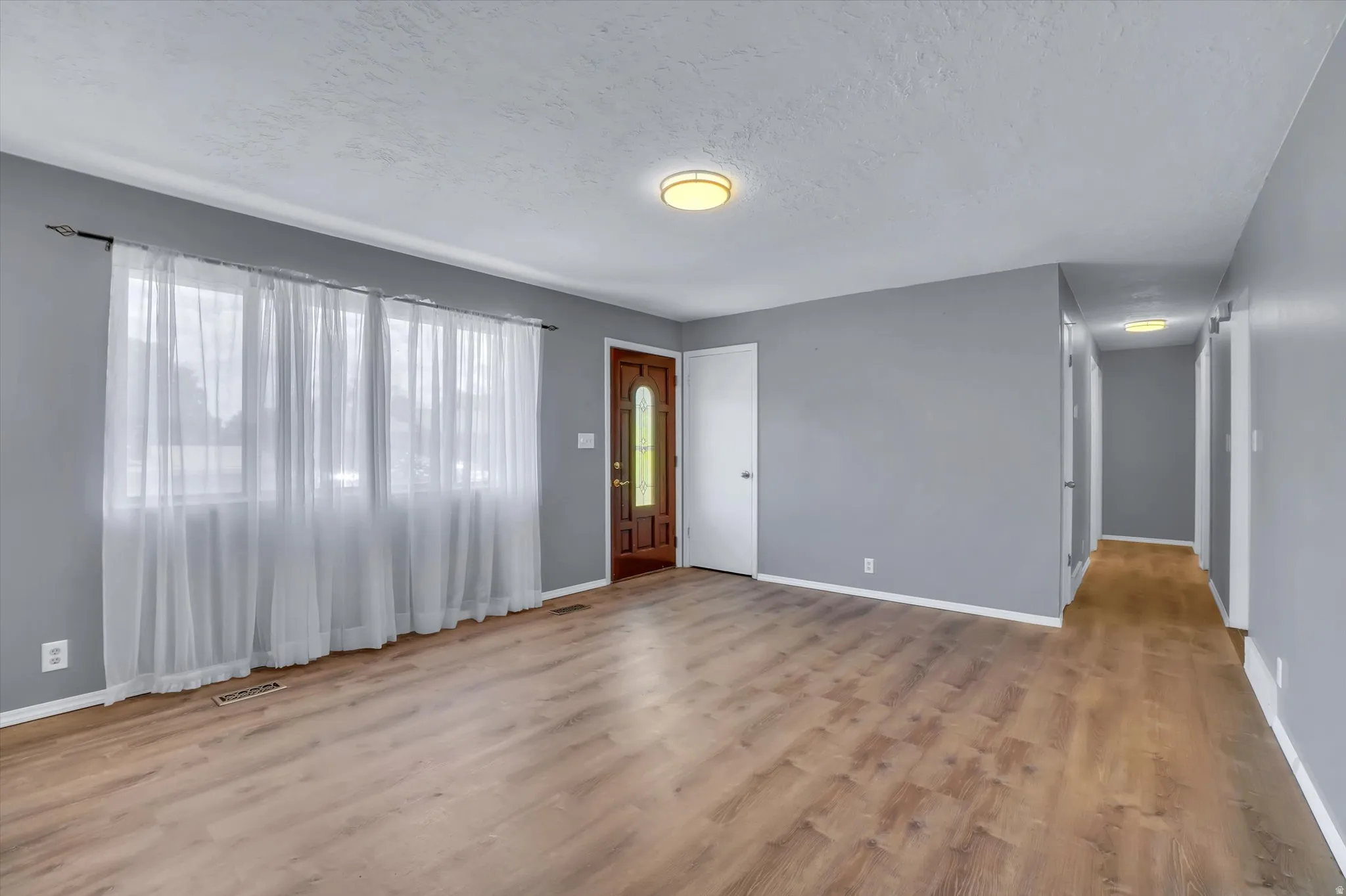 Expansive room featuring wood-finish flooring, neutral gray wall paint, and white trim