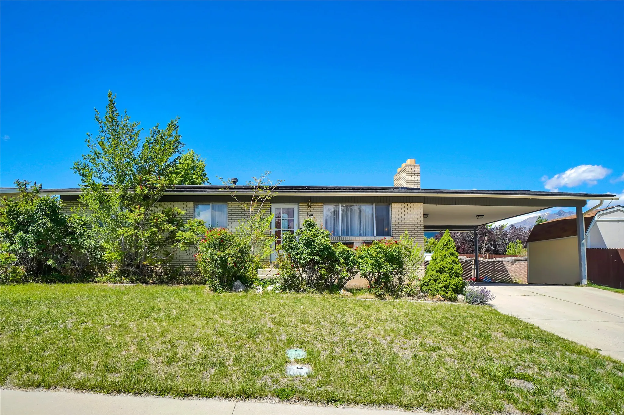 Ranch-style residence featuring a brick facade, covered carport, and a prominent chimney