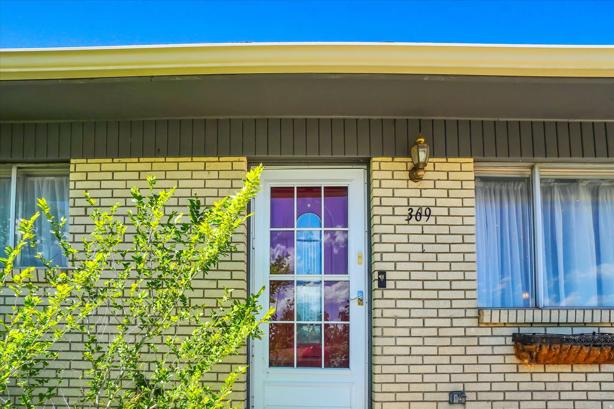 Front exterior featuring light-colored brick siding and a white entry door with divided lites