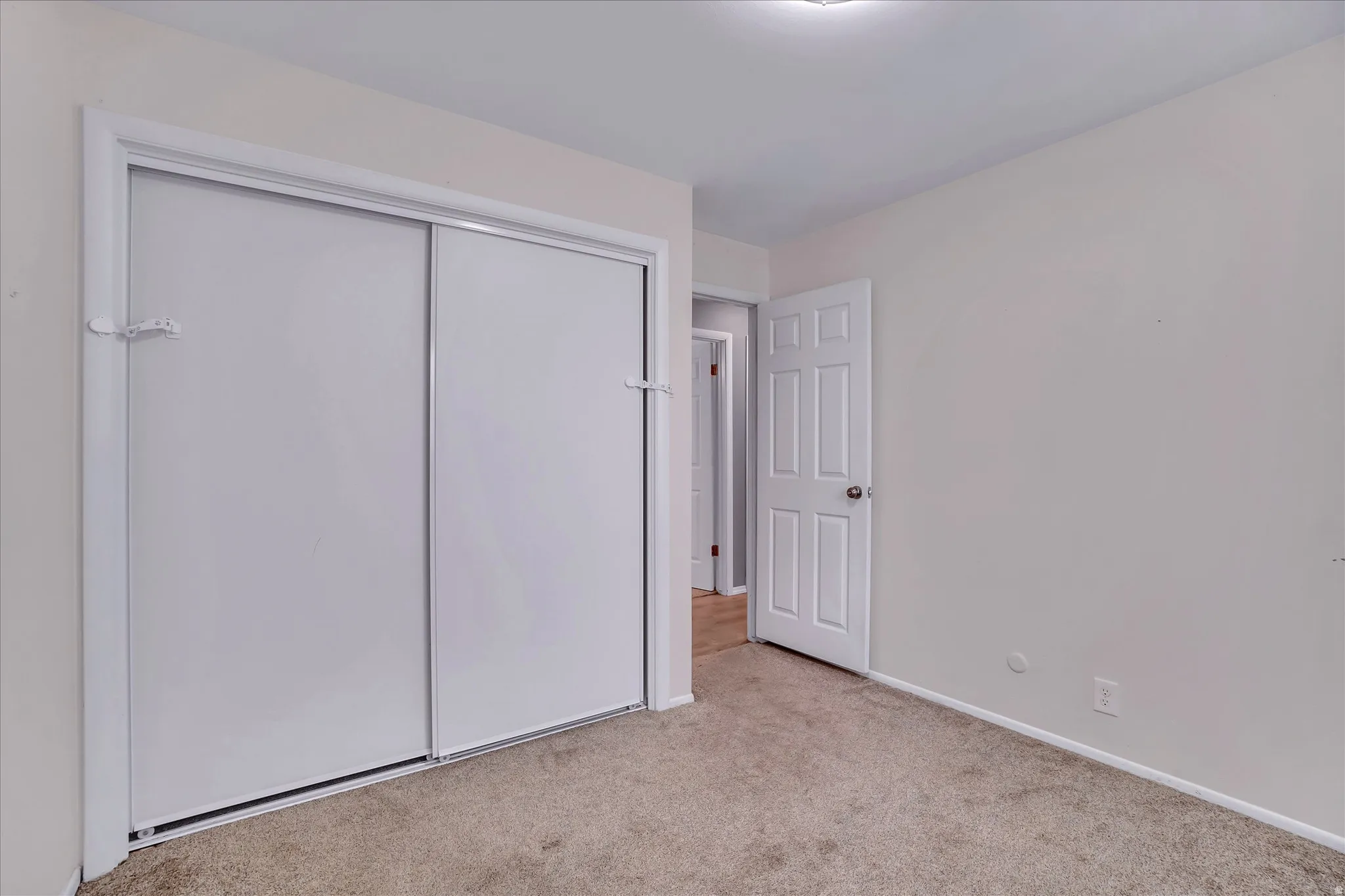 Carpeted room featuring a double-door sliding closet and a paneled entry door