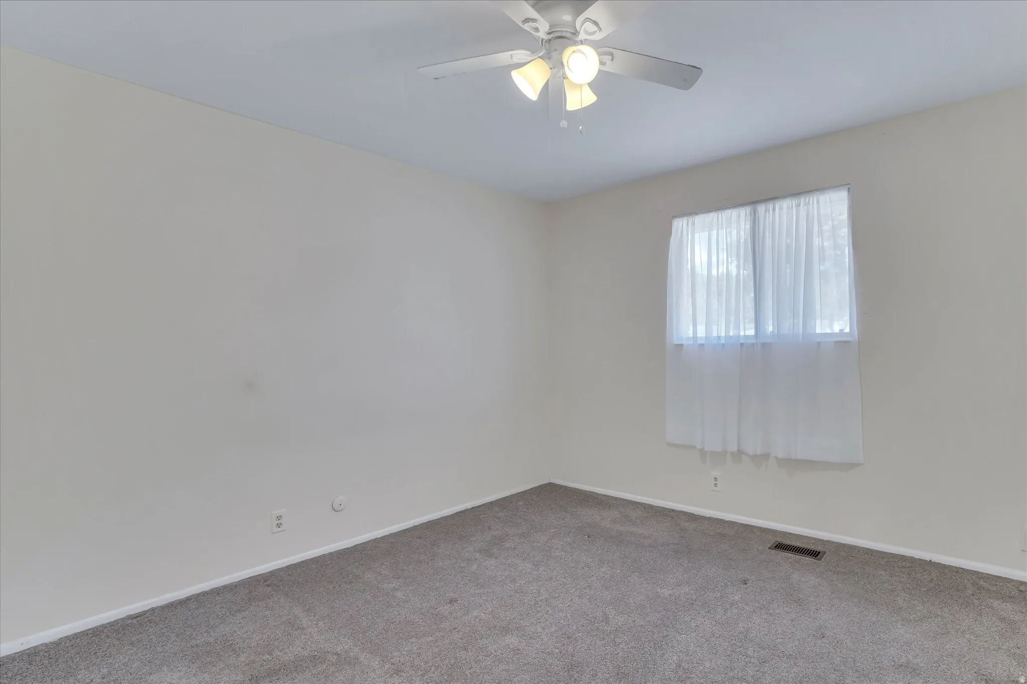 Neutral-toned room with carpet flooring and a ceiling fan with integrated lighting