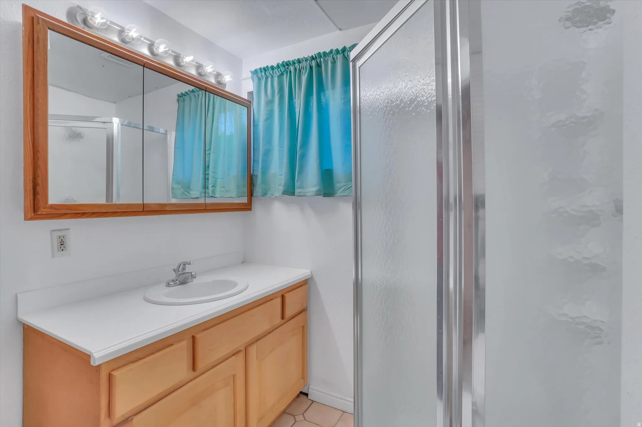 Bathroom featuring a light wood vanity, white countertop, and an integrated sink