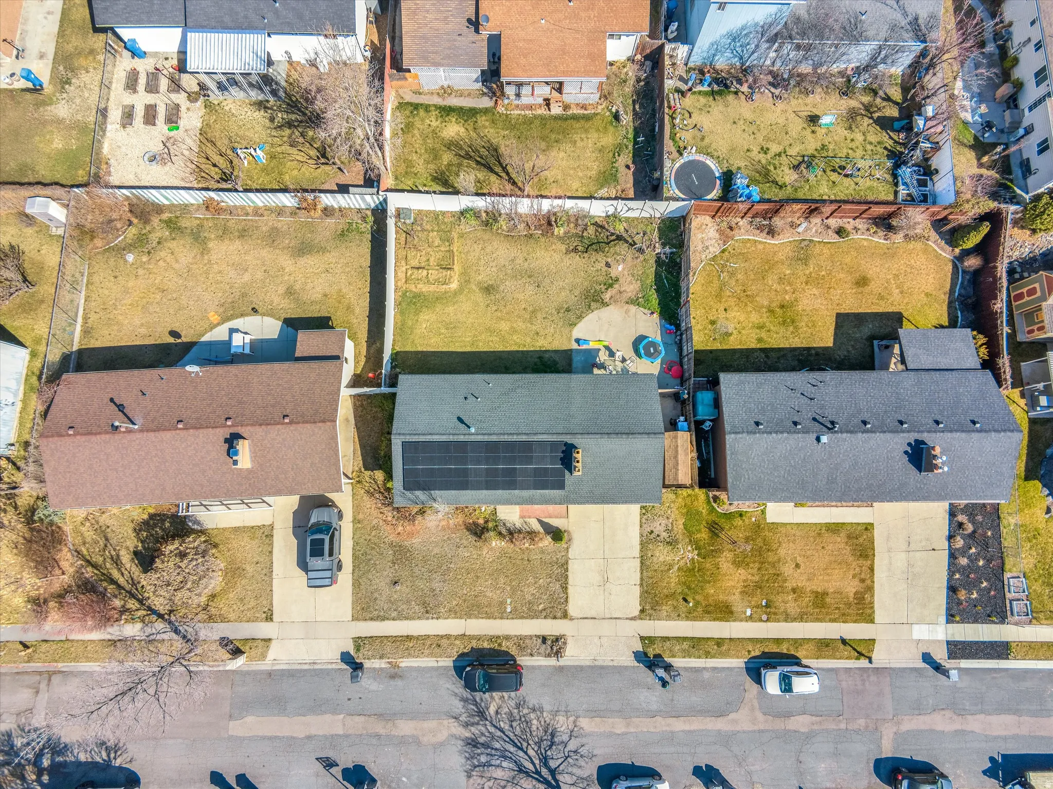 Aerial view of a residential property with a dark shingle roof and solar panels