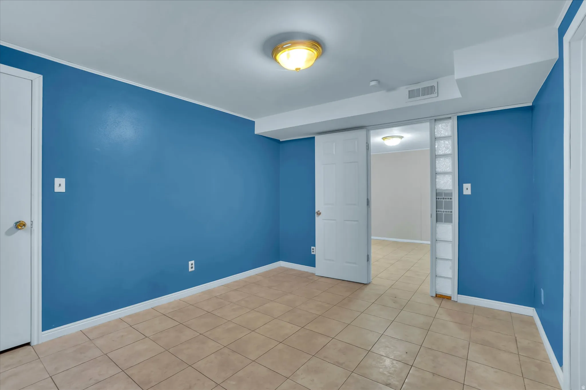 Room with blue walls, light-toned tiled flooring, and white baseboards