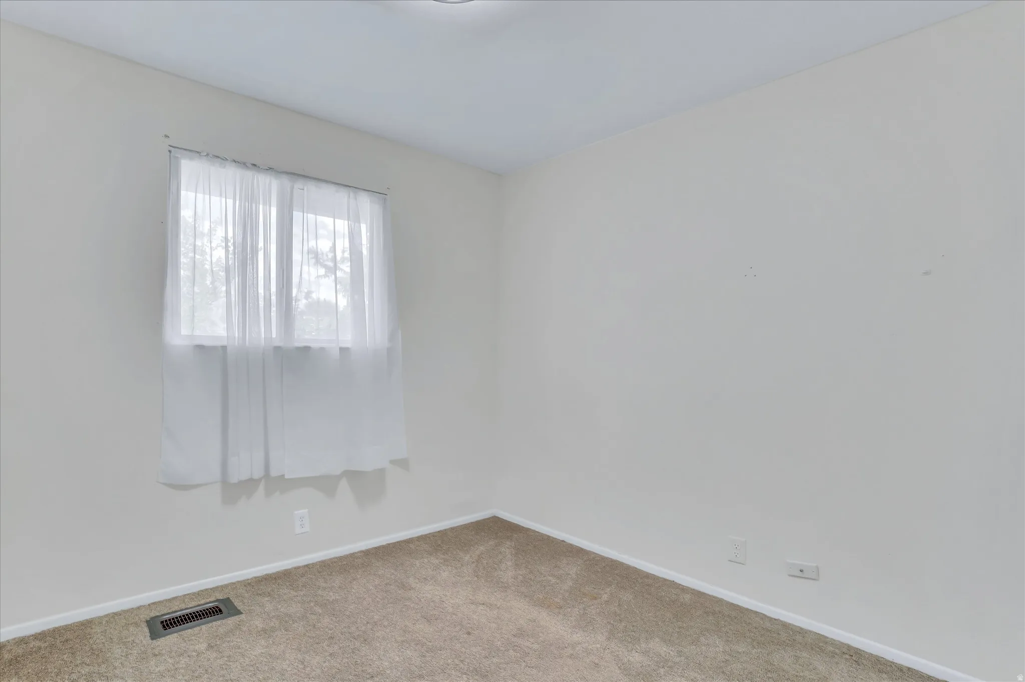 Interior room featuring light-colored walls and neutral carpeting