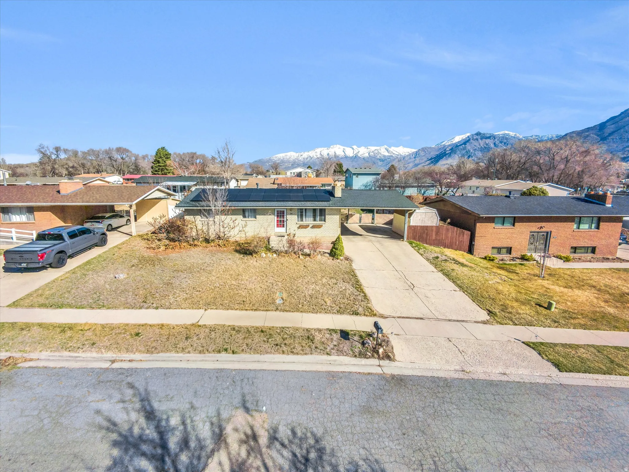 View of front of home featuring solar panels, concrete driveway, a mountain view, and a chimney