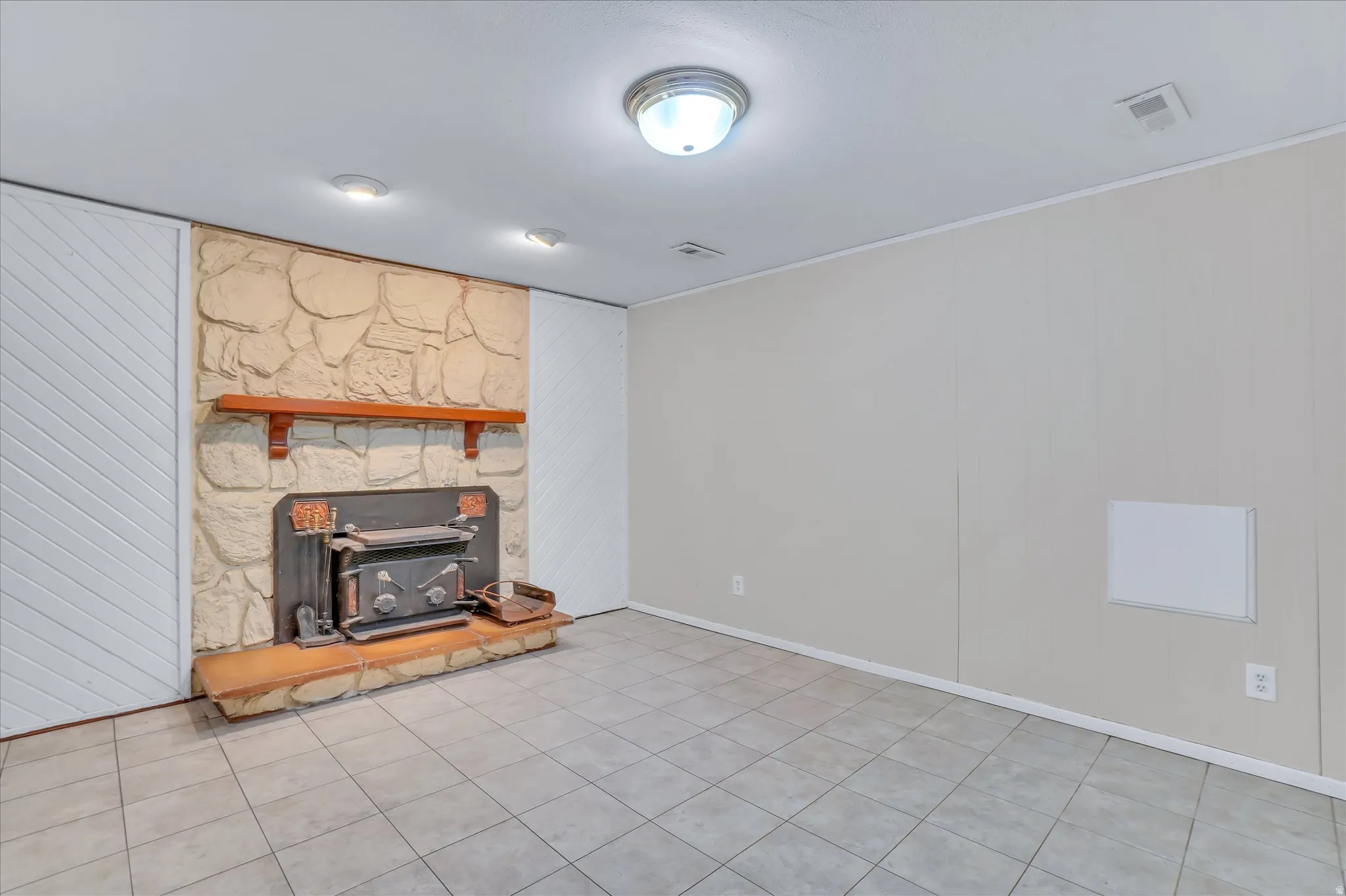 Stone-clad fireplace with a wood-burning stove and a wood mantel