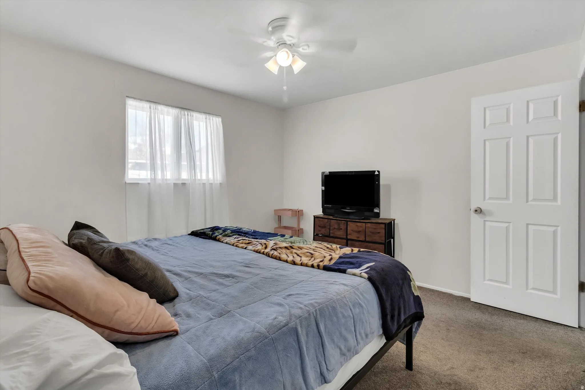 Carpeted bedroom with ceiling fan and baseboards