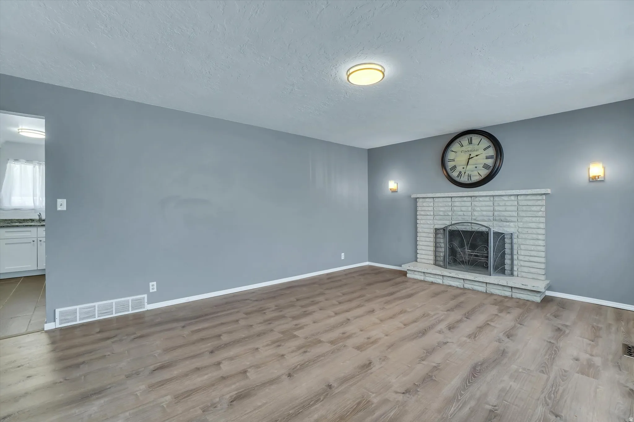 Living area featuring wood-finish flooring and a fireplace with a light-toned brick surround