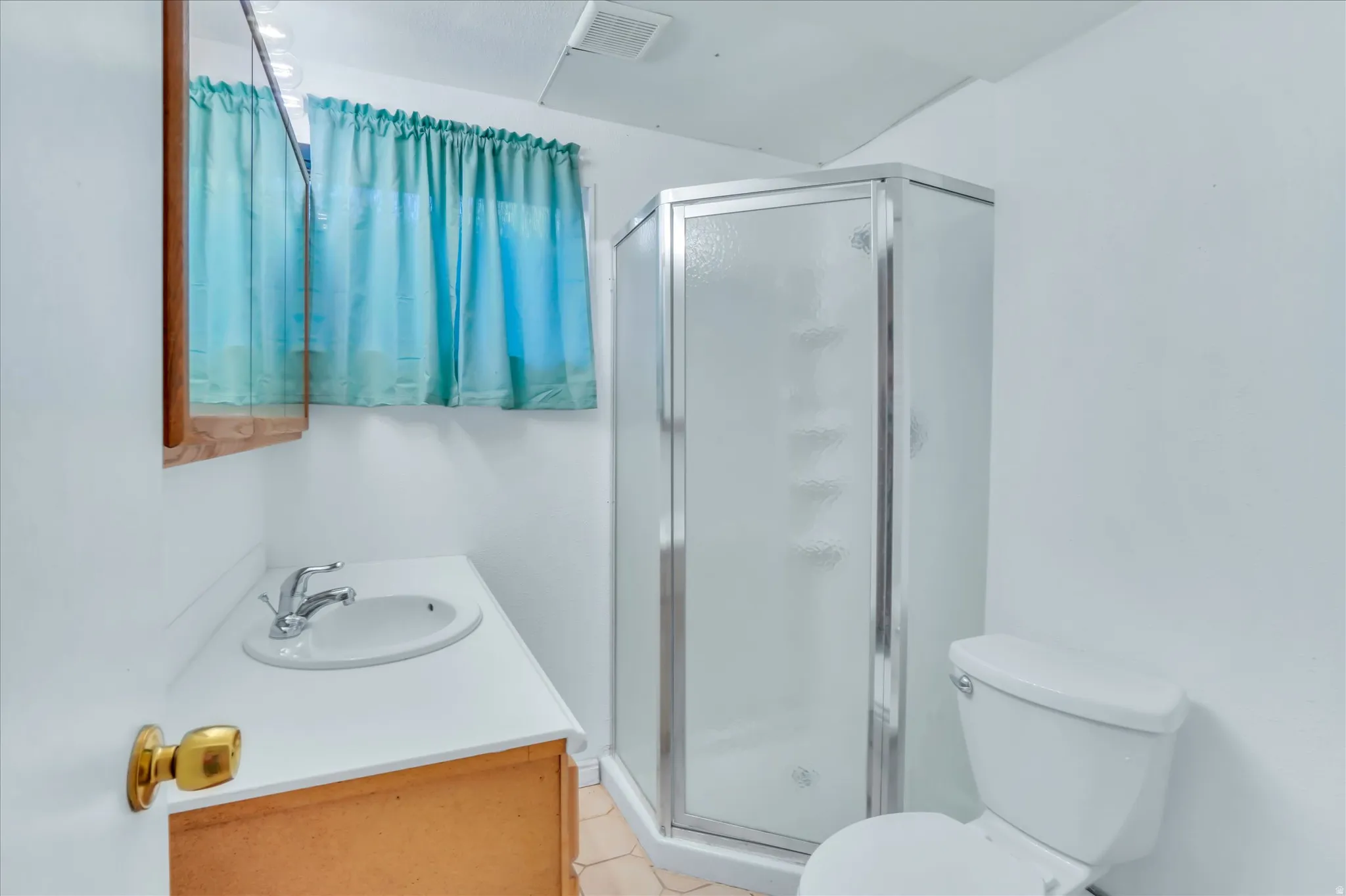 Bathroom featuring a corner shower enclosure with frosted glass panels, a single vanity with an integrated sink and laminate countertop, a medicine cabinet with a wood-finish frame, and a white toilet